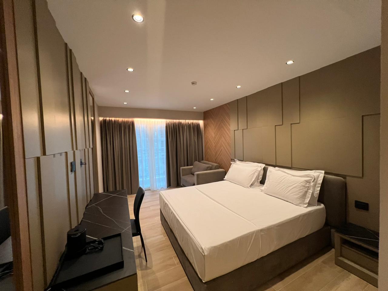 Bedroom with layered taupe panels, walnut details and a dark stone desk